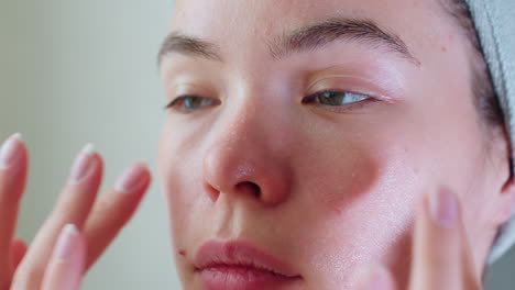 close-up of woman massaging her cheeks with hands, applying skincare for a smooth, glowing complexion, focus on beauty routine emphasizing soft touch and moisturizing for healthy skin