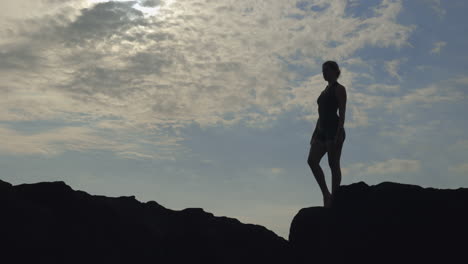 woman practicing yoga on a rocky outcrop at sunset