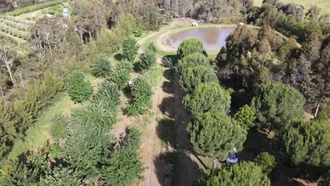 Paralaje-Aéreo-De-Drones-Sobre-Una-Exuberante-Granja-De-Permacultura-Con-Presa-Y-Una-Autocaravana