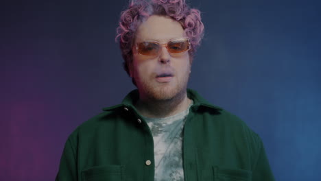 man with pink hair and sunglasses exhaling smoke