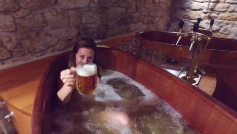 a woman in a beer spa toasts from a tub of boiling beer