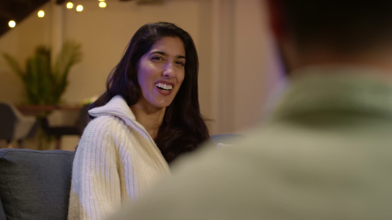 dos amigos o una pareja sentados en el sofá en casa o en un bar o café hablando juntos