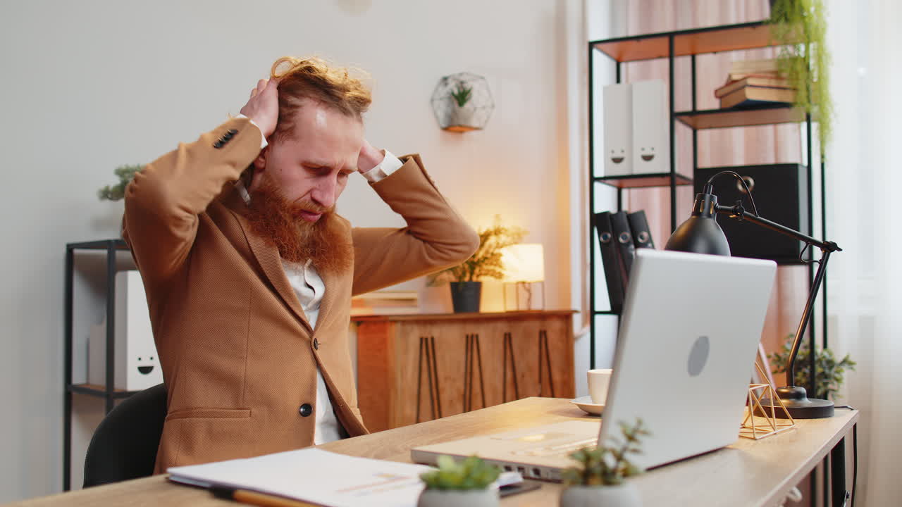 Sad businessman using laptop typing browsing, loses bad news, fortune loss fails at home office desk