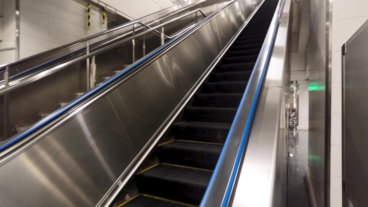 Lavvinkelbillede af en bevægelig rulletrappe på en ren, moderne metrostation i Bangkok
