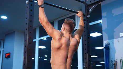 man doing exersices on horizontal bar. athlete muscular fitness male model pulling up on horizontal bar in gym
