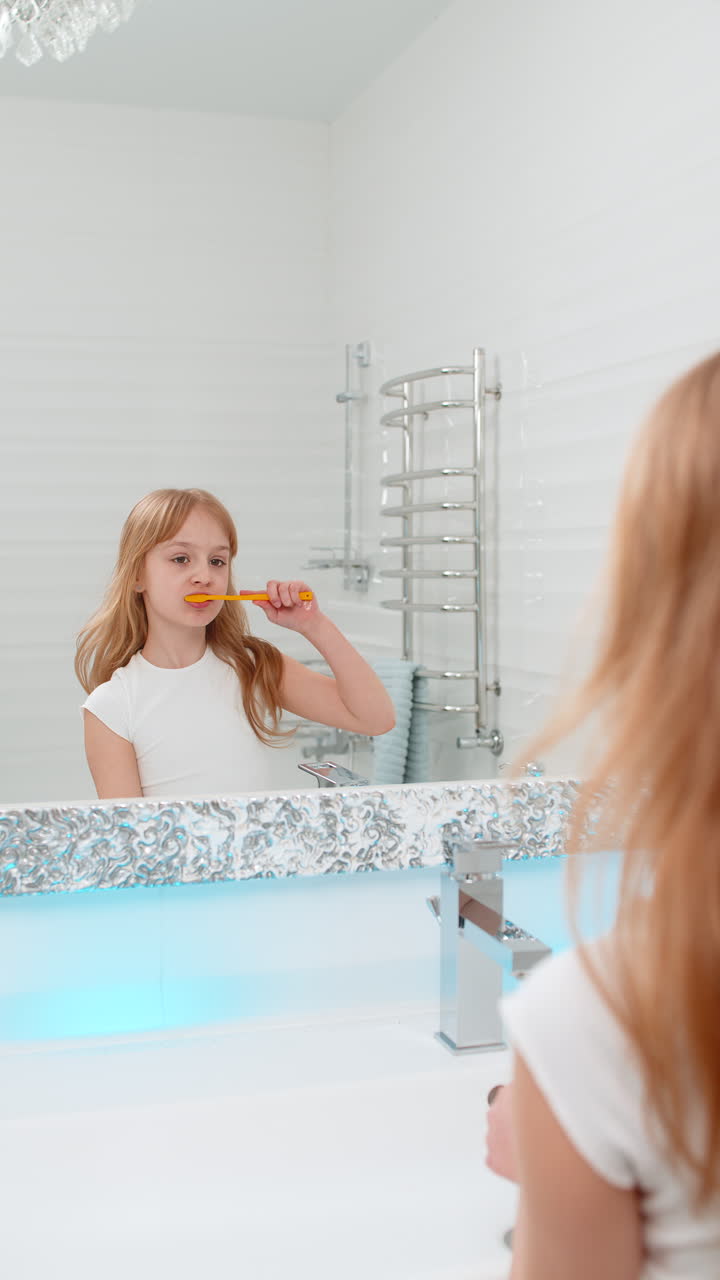 Girl brushing teeth alone in bathroom in front of mirror focusing on dental hygiene and daily care