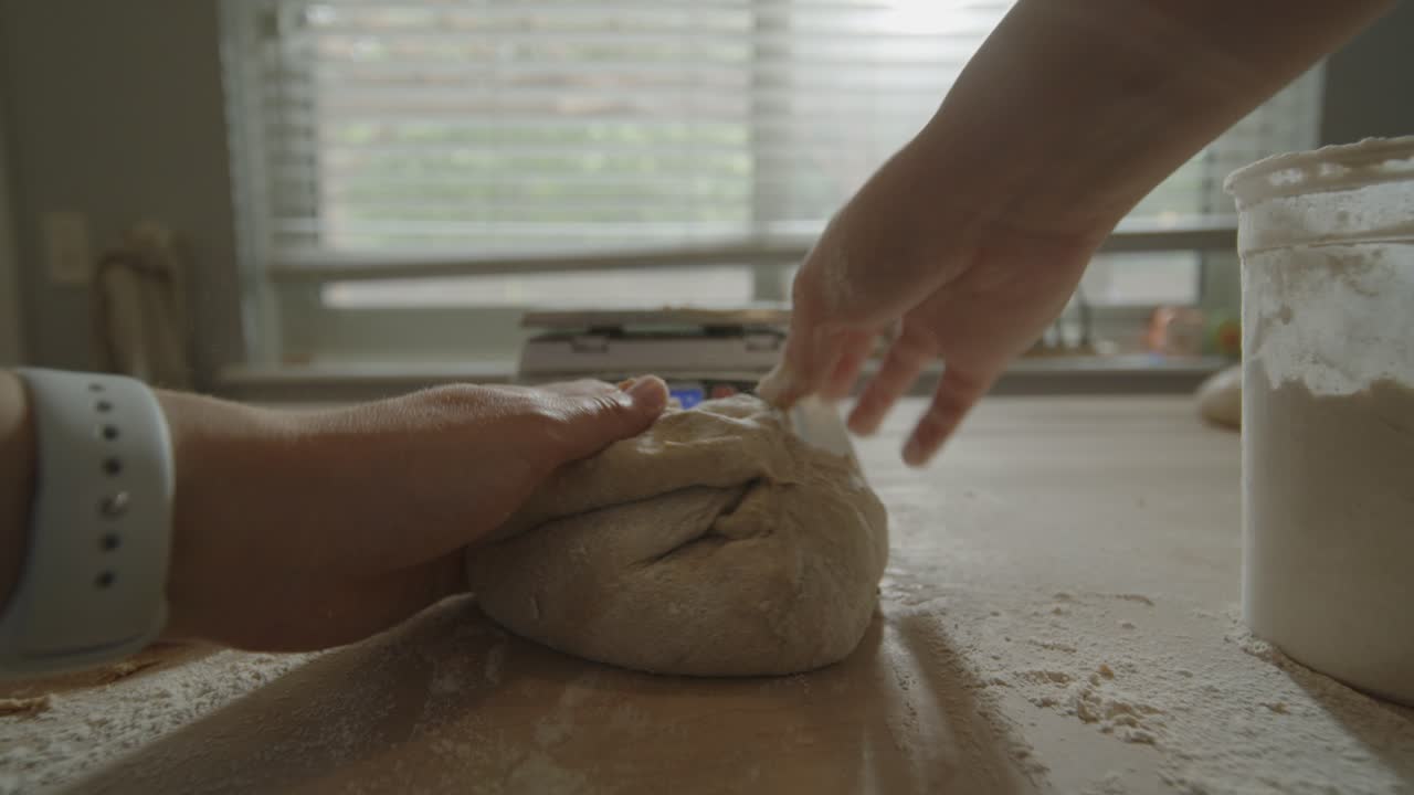 POV of hands shaping sourdough bread on kitchen counter