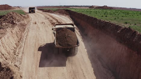 un gran camión cargado de arena se dirige hacia el sitio de construcción, fotos aéreas del camión junto con el sitio de construcción y los materiales