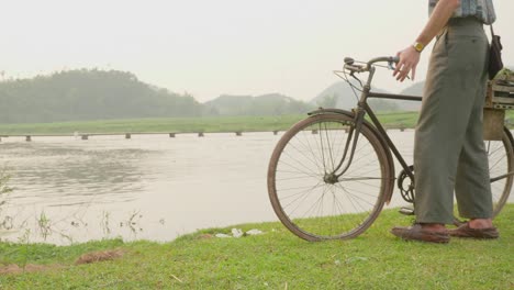 Handsome-guy-cyclist-in-cycling-clothes-and-helmet-posing-near-bicycle-looking-at-camera,-smiling