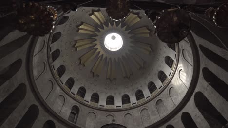 walking under lights of historic middle-eastern church, revealing high domed, decorative ceiling