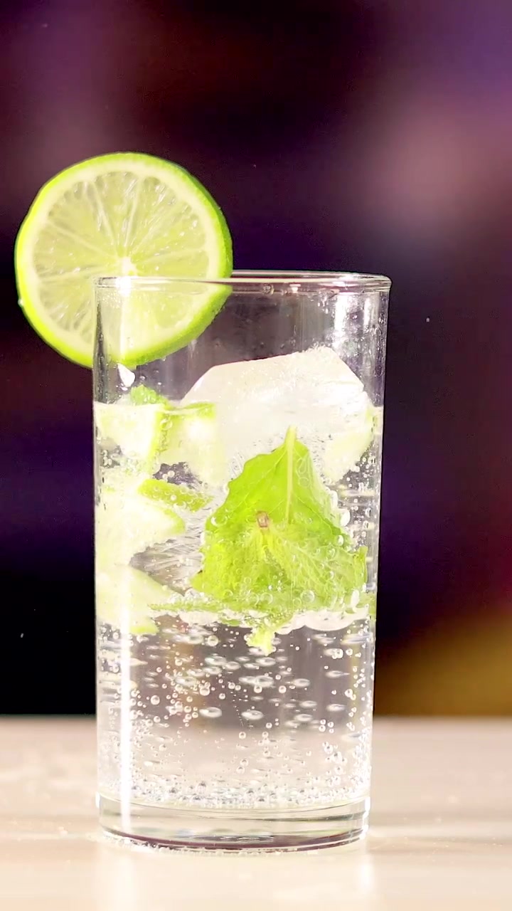Uno scatto verticale di un cocktail mojito frizzante guarnito con lime e menta fresca