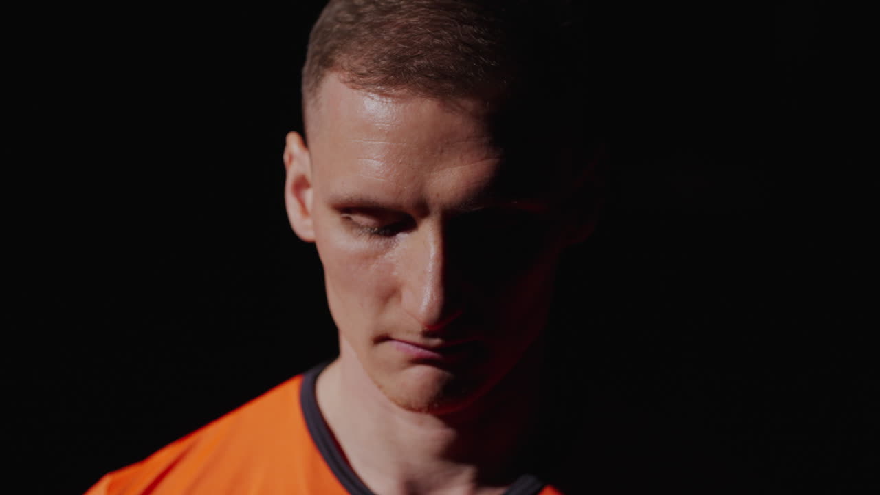 오렌지색 스포츠 셔츠를 입은 남자의 클로즈업 초상화입니다.