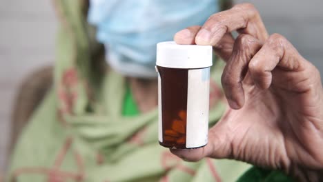 elderly woman holding a pill bottle with mask