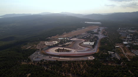 Captura-Aérea-De-Una-Pista-De-Carreras-Moderna-Ubicada-En-Un-Valle-Verde.