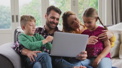 family using laptop on the sofa in a comfortable home 4k