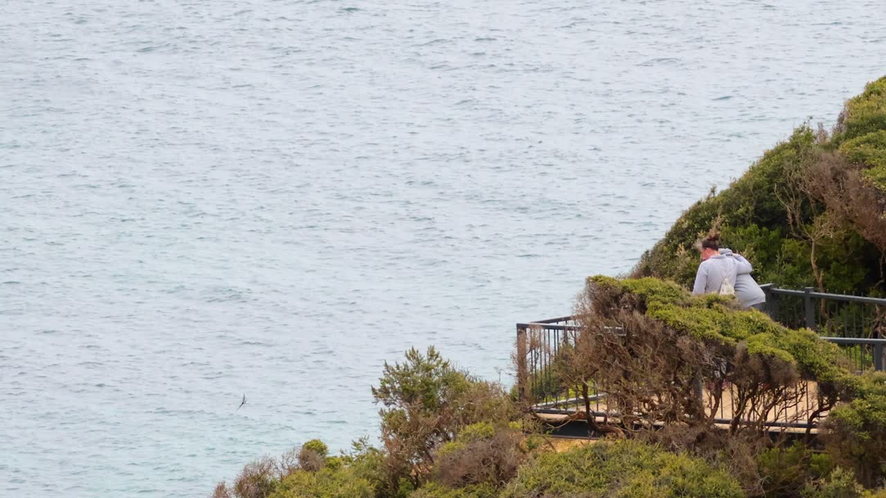 절벽 꼭대기 에서 바다 를 바라보는 사람