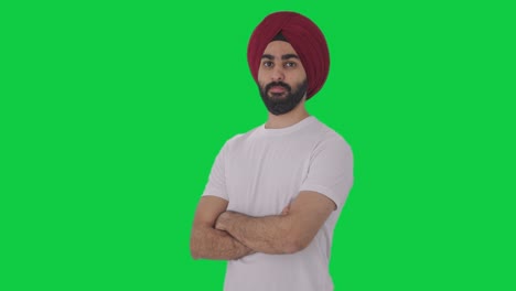 portrait of confident sikh indian man standing crossed hands green screen