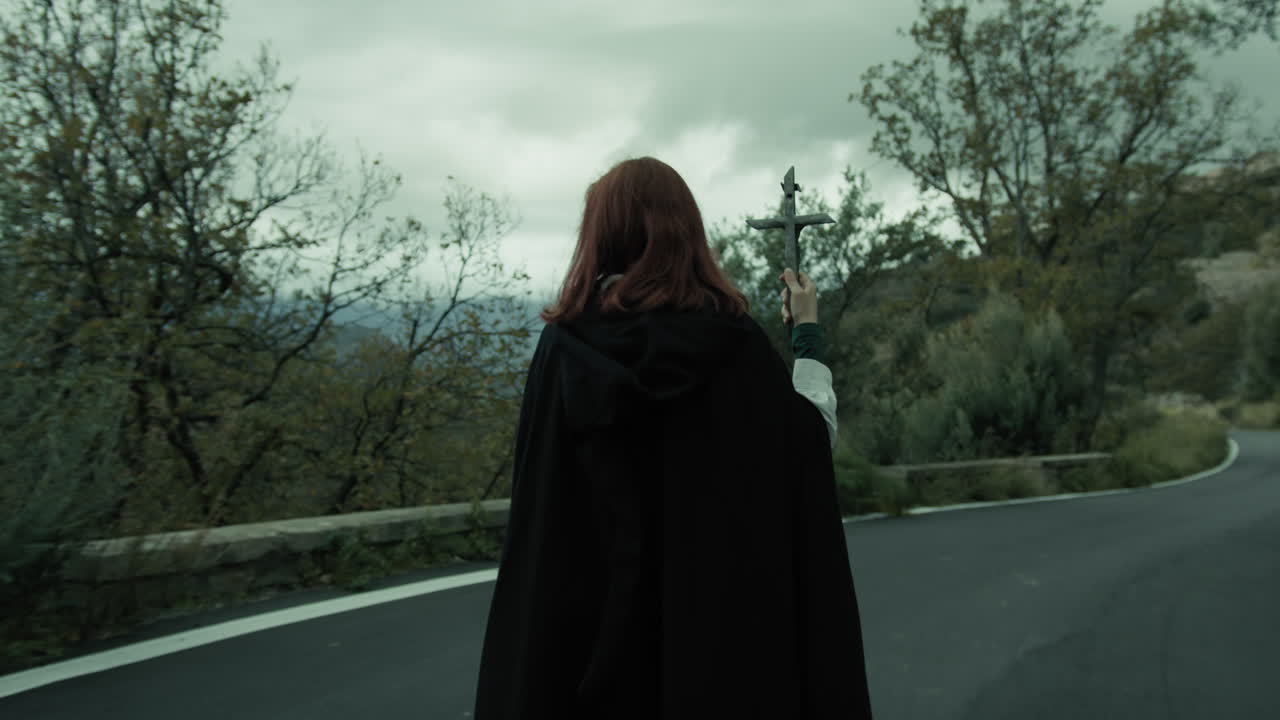 종교적인 여성이 예수 십자가를 손에 들고 거리에서 에소테릭 행렬을 고 있습니다.