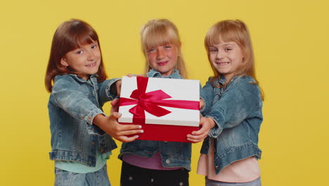 Three-girls-siblings-friends-presenting-birthday-gift-box-with-red-ribbon-holidays-sale-discount