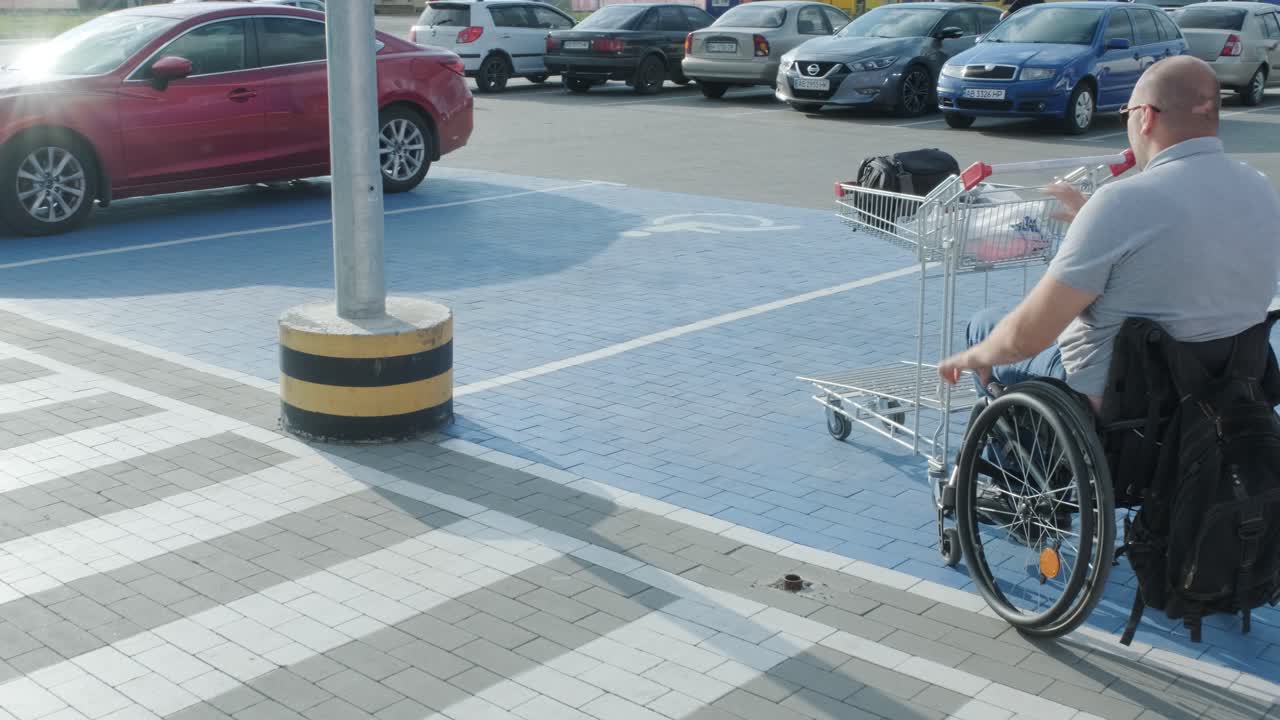 Man with disabilities in wheelchair pushing cart in front of himself at supermarket parking