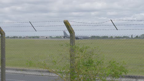 military aircraft taxiing behind barbed wire fence at raf mildenhall airfield, uk