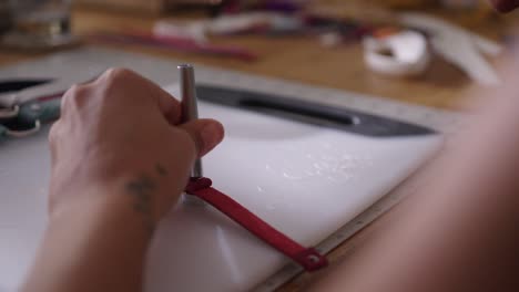 in her workshop, a hispanic artisan meticulously handcrafts leather collars, employing a wooden hammer or mallet to shape each piece with precision