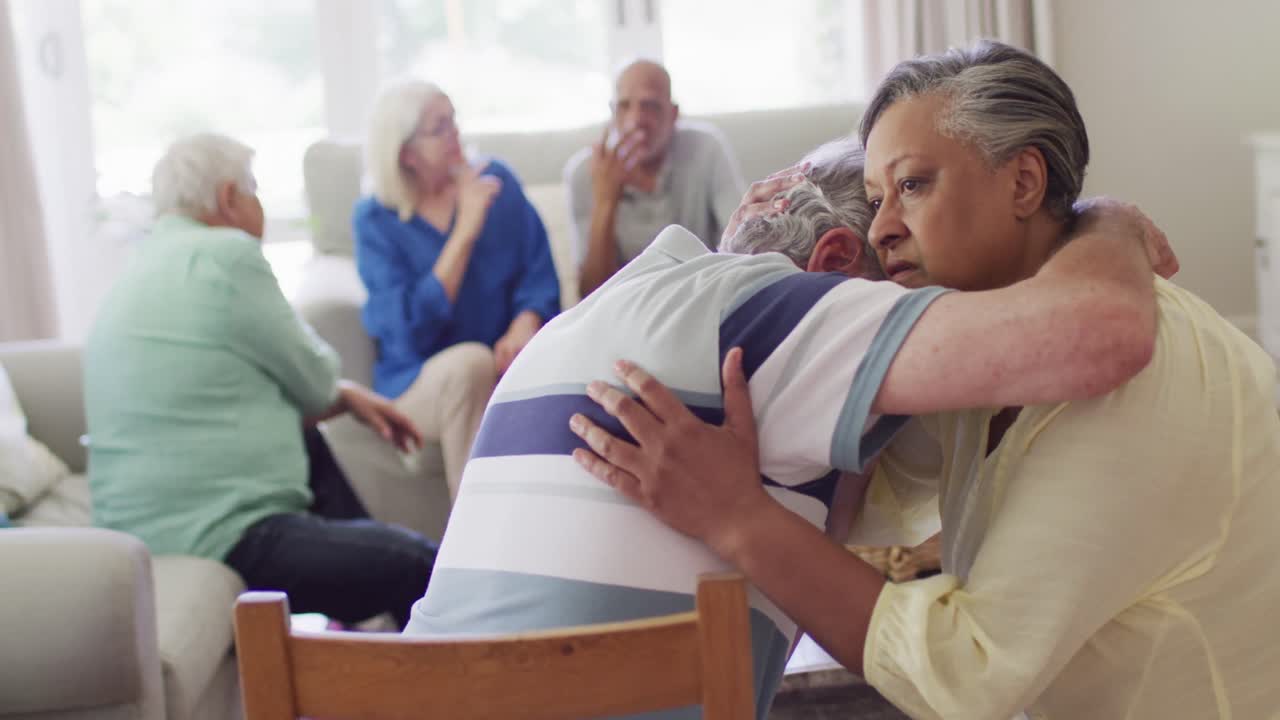 지원 그룹에서 슬픈 다양한 노인 남성 친구를 위로하는 노인 두 인종 여성, 느린 동작