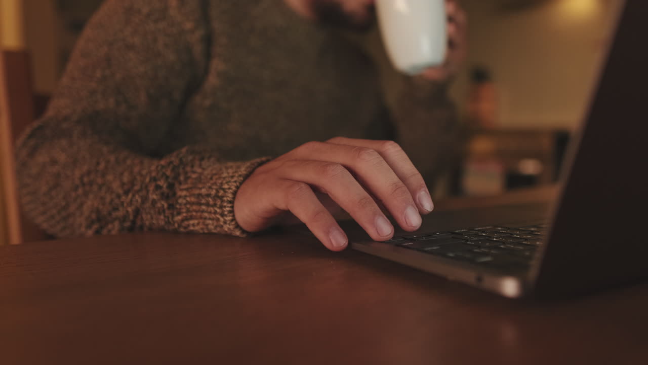 Person working on a laptop with a mug of coffee
