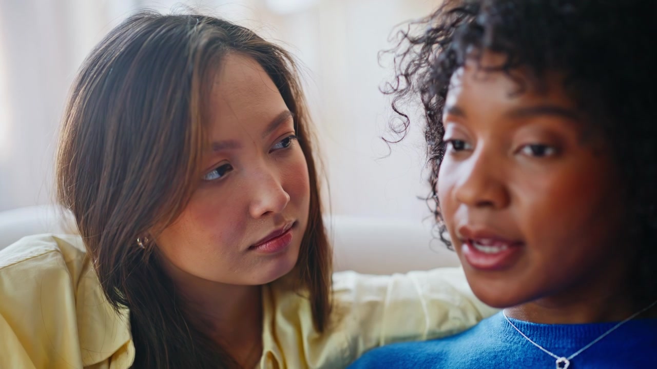 Young women having heartfelt conversation home. Closeup hands holding comfort.