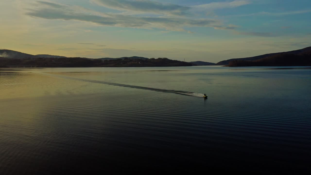 폴란드 무차르즈의 해가 지는 동안 무차르스키 호수에서 제트 스키를 타고 있는 남자의 파노라마 전망