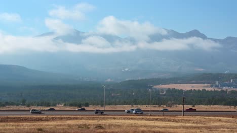 Traffic-passing-in-front-of-mountain-on-sunny-day