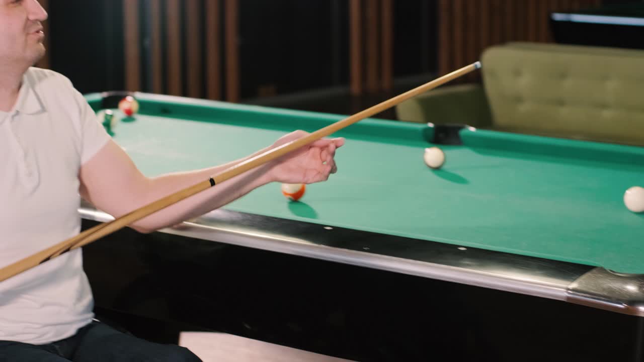 Adult men with disabilities in a wheelchair play billiards in the club