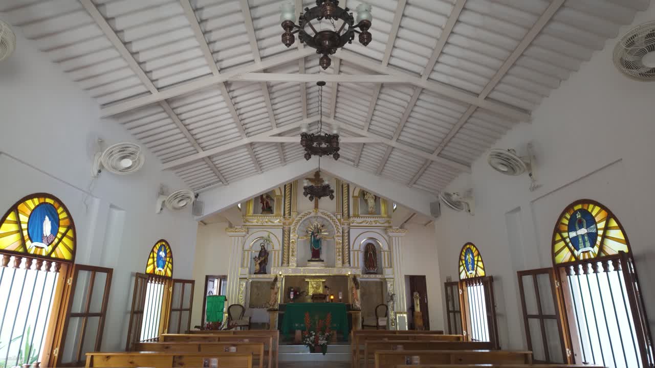 Church of Minca with ornate chandeliers and white wooden beams on the ceiling