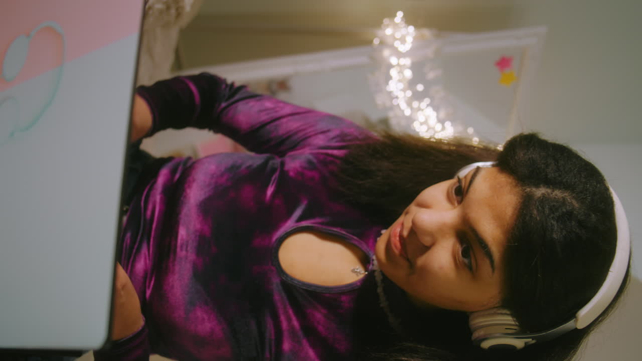 Teenage girl using laptop in bedroom