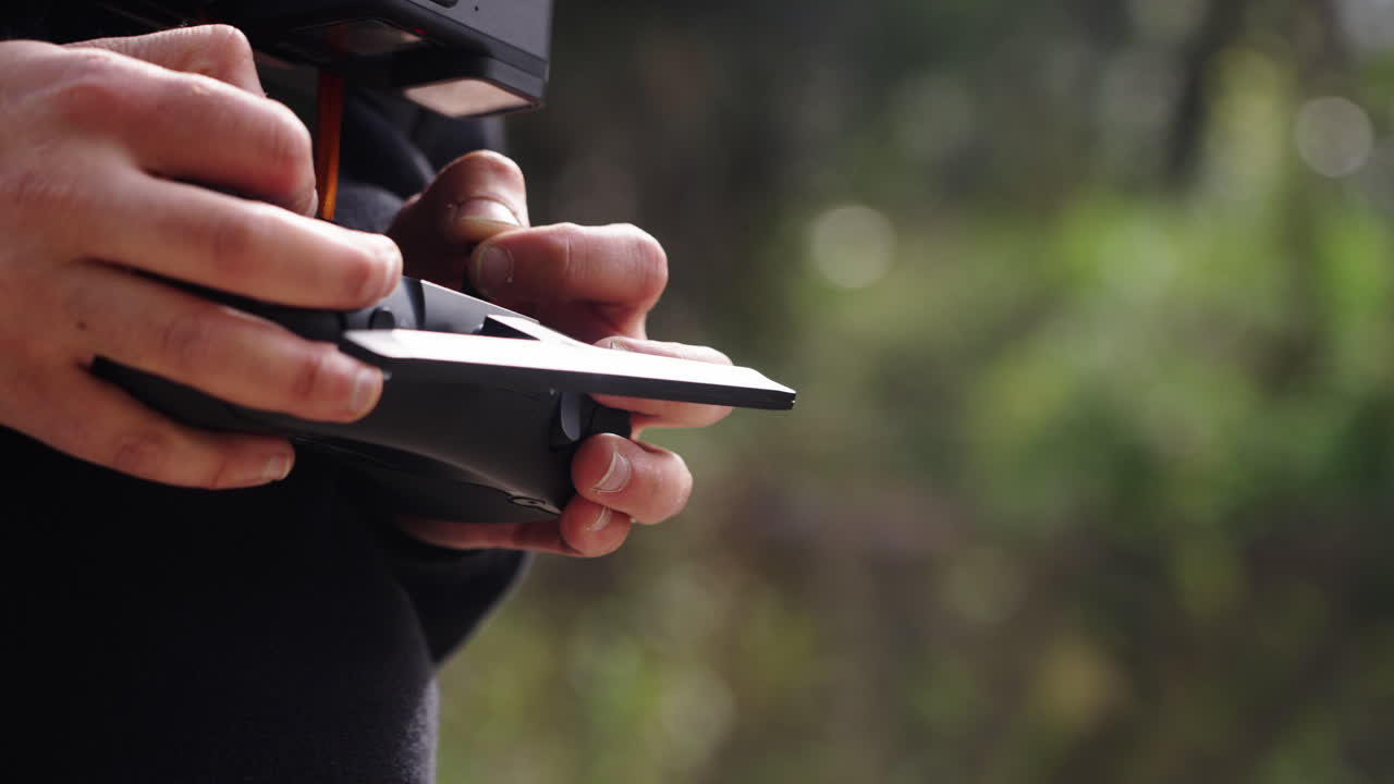 Primo piano delle mani che azionano un telecomando per drone all'aperto.