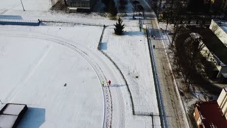 Winter-running-on-snowy-running-track,-snowy-pitch-and-running-aerial-shot