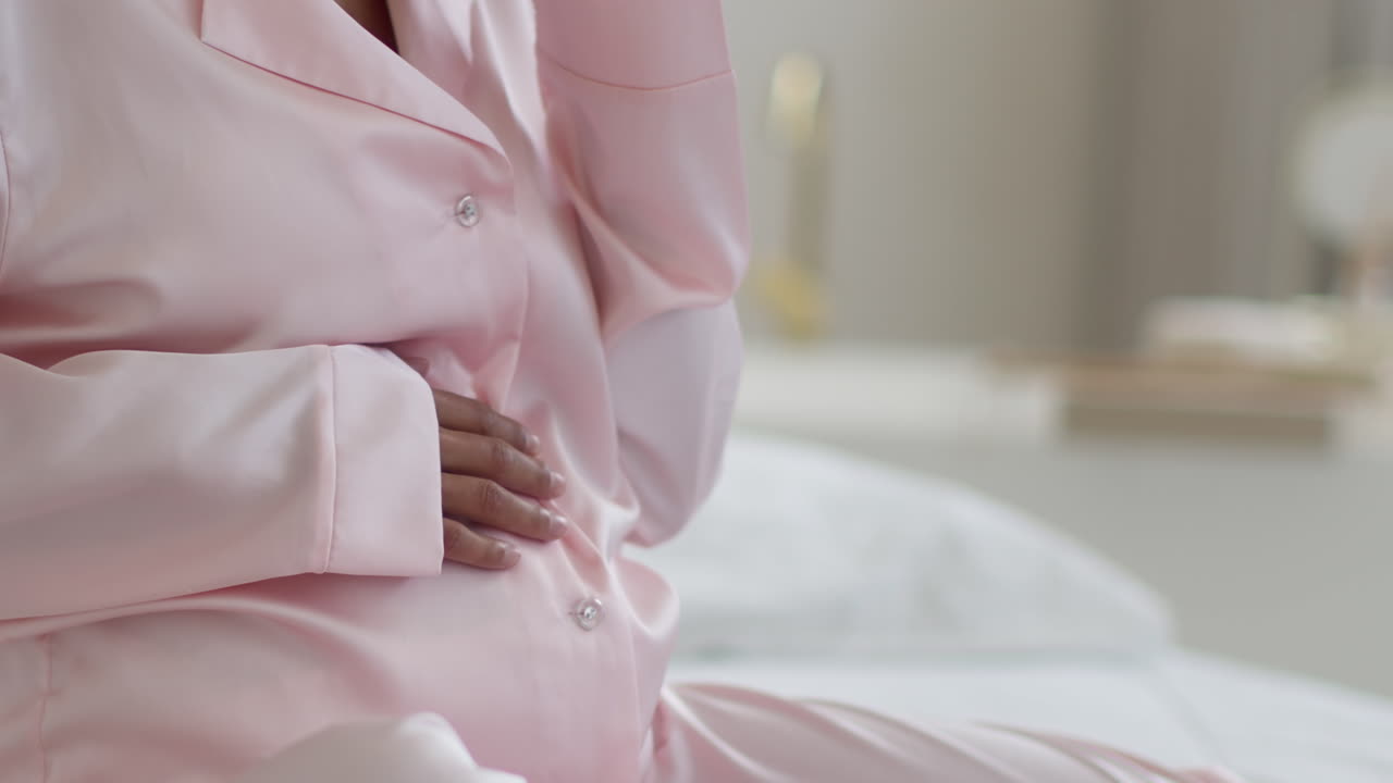 Pregnant woman in pink pajamas smoking a cigarette