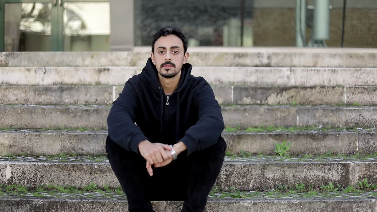 Serieuze jonge man zittend op de trap
