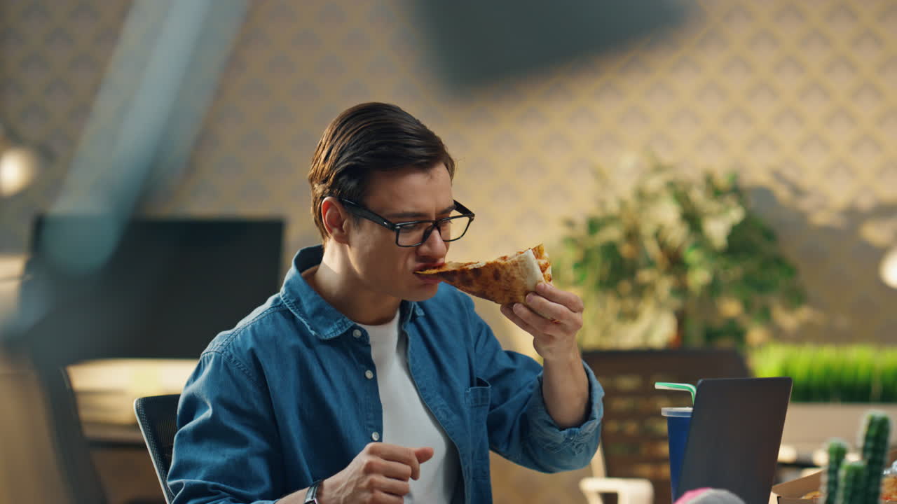 hombre hambriento tomando una rebanada de pizza en la oficina de primer plano. dos startups disfrutando del almuerzo