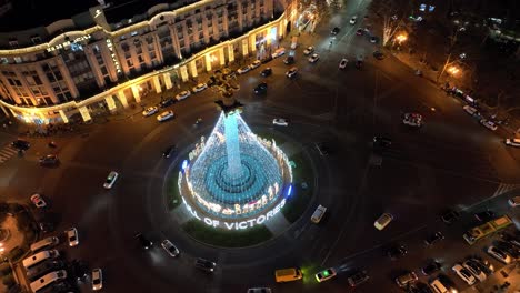 a glowing christmas tree in the middle of a busy roundabout, with light trails from moving cars. the surrounding historic buildings complement the festive scene, adding an old-world charm