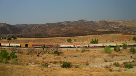 Union-Pacific-Tran-along-the-track-near-Caliente,-California-with-ash-from-wildfire-burns-in-the-hills-behind