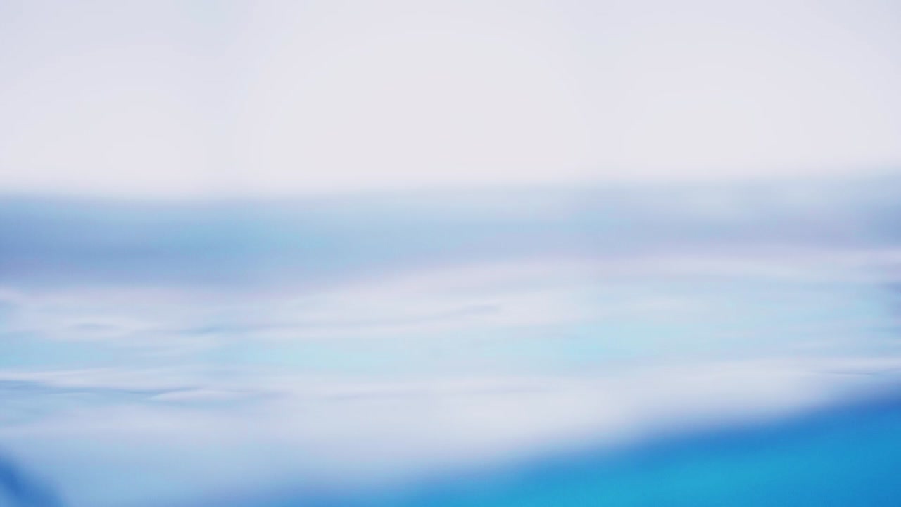 The clean water surface in slow motion fills the screen with water splashing shop the water drop and waving liquid surface with an air bubble