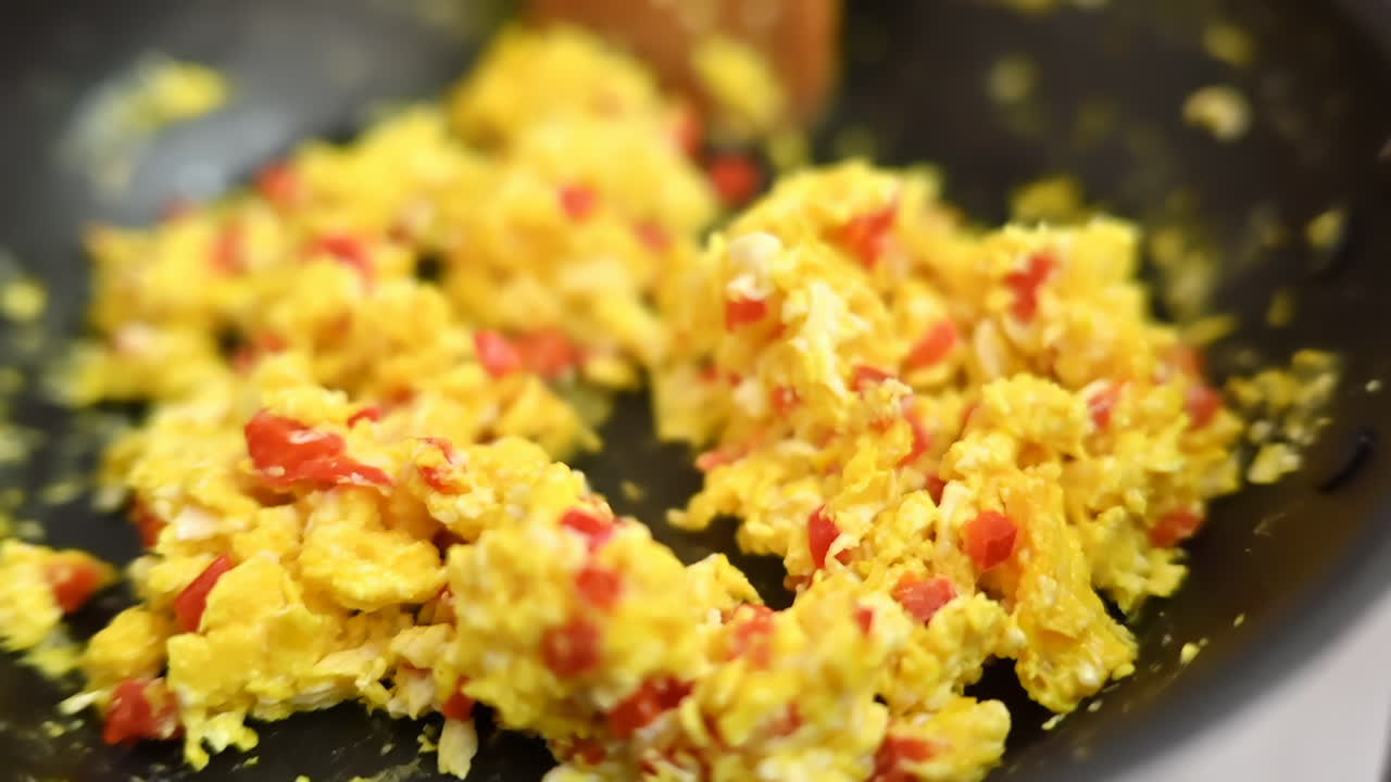 Omelette preparation on a black pan, slow motion