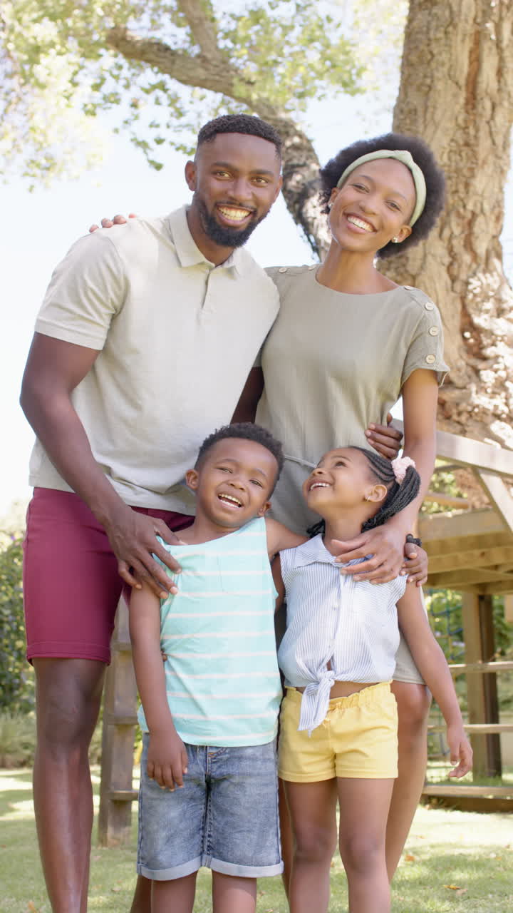 Vertical video of portrait of happy african american family in garden, in slow motion