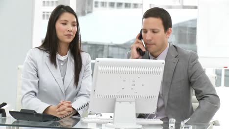 Two-young-businesspeople-working-at-a-computer