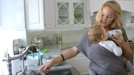 Busy-Mother-With-Baby-In-Sling-At-Home