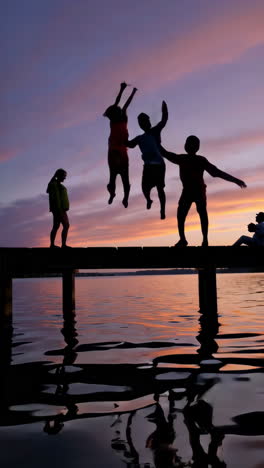 silhouettes of friends on a pier at sunset
