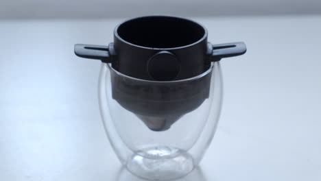 scooping ground coffee into pour over filter in a double wall glass