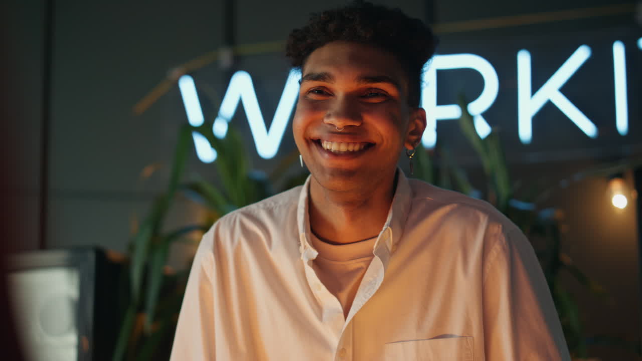 Primo piano di un ragazzo sorridente che ride in un bar notturno. L'uomo si sente felice.