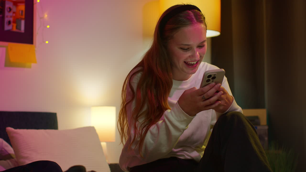 una mujer joven riendo mientras mira su teléfono.